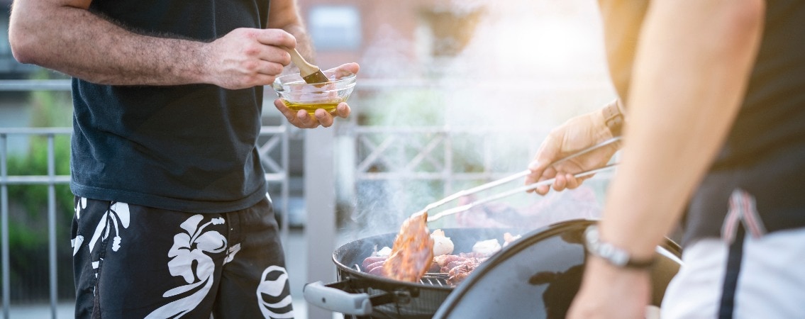 Zwei Männer grillen auf dem Balkon